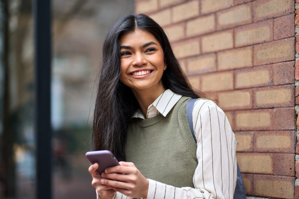 Happy Asian teen girl college student girl using smartphone on street.